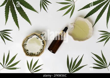 Ingrédients cosmétiques naturels pour les soins de la peau et des cheveux. Feuilles de chanvre vert. Flacons en verre avec vue de dessus et produit sur fond blanc. Vue de dessus Banque D'Images