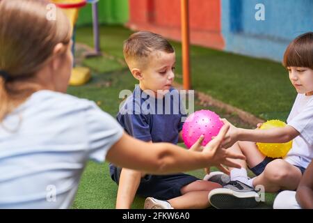 Professeur de gym jouant au ballon avec les enfants faisant des sports pour les enfants préscolaire ou garderie Banque D'Images