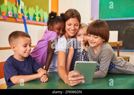 L'enseignant de maternelle et les enfants prennent un selfie dans la maternelle internationale pour les médias sociaux Banque D'Images