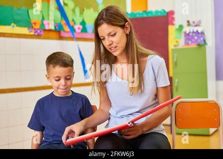 Éducateur ou enfant en train de lire un livre à l'école maternelle ou centre de soins après l'école Banque D'Images