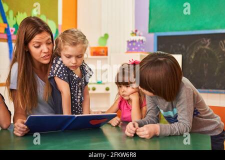 Un enfant lit un livre à un groupe d'enfants dans préscolaire ou maternelle Banque D'Images