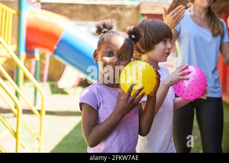 Les enfants jouent au bal dans un cours d'éducation physique avec un professeur de gymnastique dans la maternelle internationale Banque D'Images