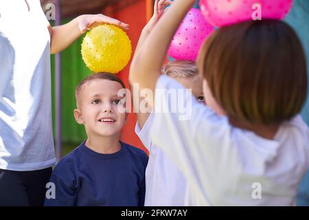 Les enfants s'amusent à jouer au ballon devant la maternelle dans la classe d'éducation physique Banque D'Images