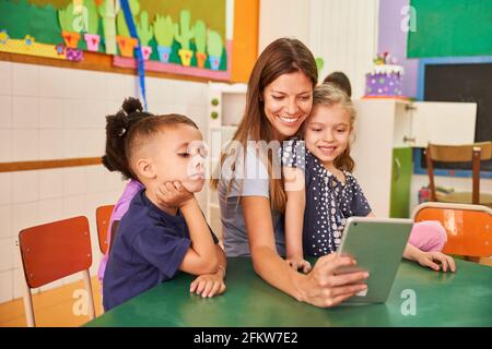 L'enseignant de maternelle et les enfants prennent un selfie avec un ordinateur tablette en ligne sur les réseaux sociaux Banque D'Images