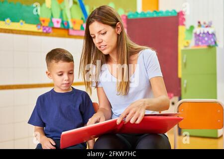 Professeur de maternelle ou de maternelle lisant un livre pour un enfant en garderie ou en centre de soins après l'école Banque D'Images