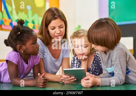 Les enfants et les éducateurs lisant à haute voix un ebook ou un apprentissage sur la tablette Banque D'Images