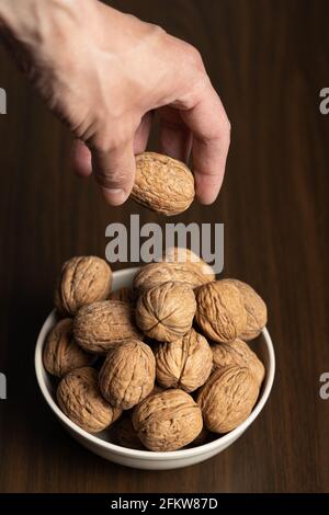 Main de l'homme ramassant une noix dans un bol Banque D'Images