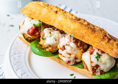 Sous-sandwich Meatballs avec fromage et sauce tomate dans une baguette sur une assiette blanche. Banque D'Images