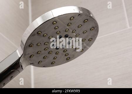 Tête de douche isolée sur fond crème. Douche dans la salle de bains. Banque D'Images