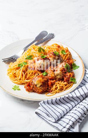 Spaghetti aux boulettes de viande, au fromage et à la sauce tomate dans un plat blanc. Banque D'Images