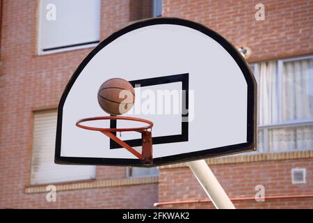 Regardez le ballon de basket-ball sur le point d'entrer dans le panier sur le court de rue Banque D'Images