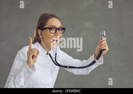 Une femme médecin avec une bouche ouverte, portant largement le stéthoscope, comprend quelque chose Banque D'Images