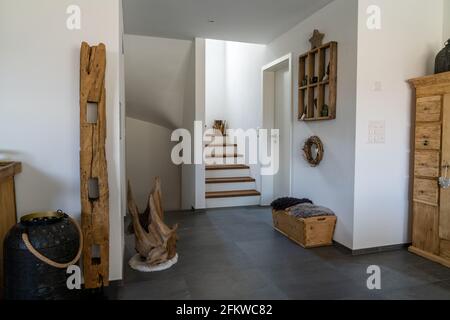 Vue intérieure sur un hall élégant et des escaliers avec carrelage noir, murs en plâtre blanc et mobilier en bois et articles décoratifs Banque D'Images