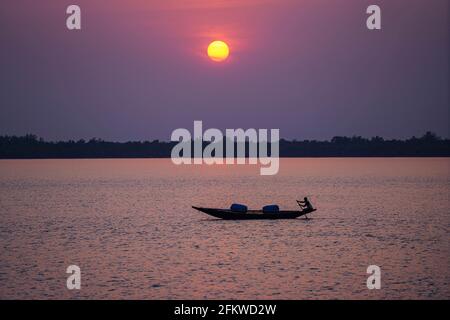 Le pêcheur recueille des frayeurs sur la rivière Shibsa au coucher du soleil près des Sundarbans, la plus grande forêt de mangroves naturelles du monde à Khulna. Banque D'Images