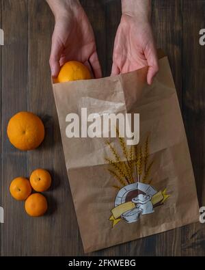 Les paumes des mains masculines tiennent un sac orange et un sac en papier, pour représenter la protection de la planète avec des matériaux éco-durables et une production zéro kilomètre Banque D'Images