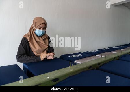 Kota Kinabalu, Sabah, Malaisie-mars 05, 2021 : lady travailleur avec masque médical préparant le t-shirt pour l'impression dans la sérigraphie table oa Banque D'Images