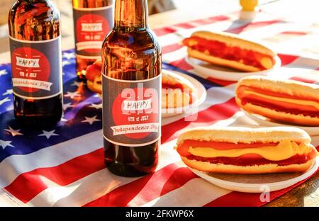 Table du 4 juillet, bouteille de bière avec étiquette originale, Happy Independence Day, hot dog classique avec catchup et moutarde, drapeau américain. Banque D'Images