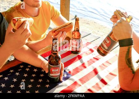 Fête de fête du 4 juillet, jeunes hommes mains tenant bouteille de bière, motif de vacances, Happy Independence Day, hot dog, moutarde, catchup. Américain Banque D'Images