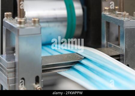 Gros plan procédé de fabrication de masques médicaux dans une usine. Machines automatisées qui font des masques médicaux respiratoires en grandes quantités. Banque D'Images