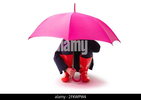 Personne portant des chaussures en caoutchouc rouge et un parapluie de pluie isolé sur fond blanc. Banque D'Images