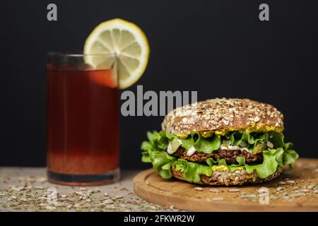 jus à côté d'un hamburger végétarien sain sur une assiette en bois Banque D'Images