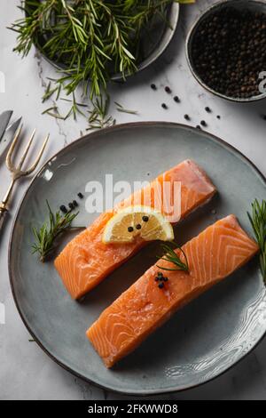Vue aérienne de deux filets de saumon servis sur une assiette avec citron et romarin sur la table Banque D'Images