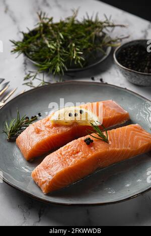 Deux filets de saumon servis sur une assiette avec citron et romarin sur la table Banque D'Images