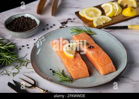 Deux filets de saumon avec citron une branche de romarin et poivre sur la table Banque D'Images