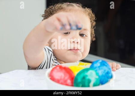 Enfant ramassant des œufs peints, des œufs de Pâques. Banque D'Images
