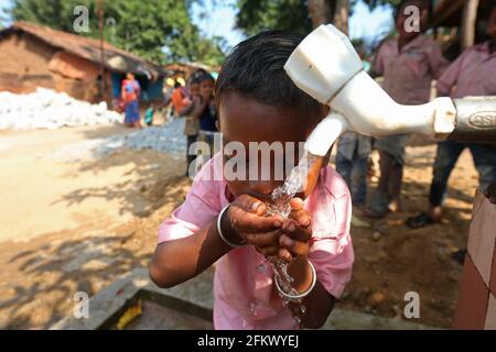 Un garçon d'école boit de l'eau au village de Lanjigadh à Odisha, en Inde. LA TRIBU DESIA KONDHA Banque D'Images