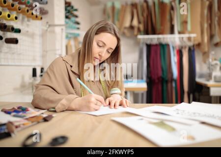 une couturier féminine travaille dans son atelier. Femme élégante en train de créer une nouvelle collection de vêtements. Banque D'Images