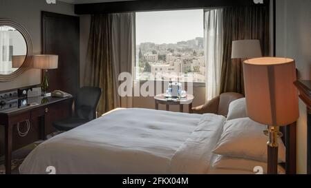 Un lit king-size fraîchement préparé dans une chambre d'hôtel confortable avec vue sur Amman, Jordanie par temps clair Banque D'Images