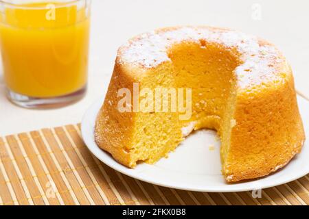 Gâteau d'orange avec un peu de sucre glace et un verre de jus d'orange. Banque D'Images