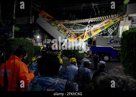 Mexiko Stadt, Mexique. 04e mai 2021. Les travailleurs humanitaires et les sauveteurs se tiennent devant les décombres après l'effondrement d'une section d'un pont sur la ligne 12 du métro à Mexico. Deux voitures tombent dans une rue animée. Il y a eu des morts et des blessures. (À dpa 'près de deux douzaines de morts dans l'effondrement du pont de métro de Mexico') Credit: Jair Cabrera Torres/dpa/Alamy Live News Banque D'Images