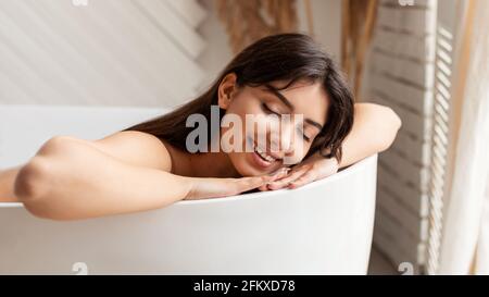 Bonne femme bain couché avec les yeux fermés détente dans la salle de bains Banque D'Images