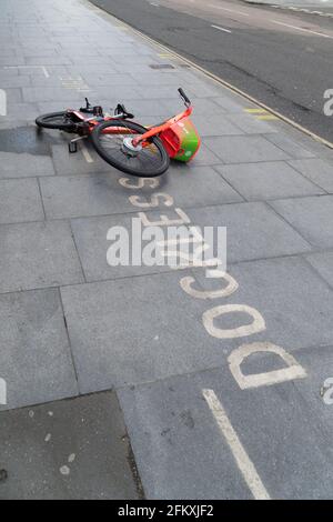 Uber Jump Electric bike à gauche à côté de dockless signe sur La chaussée du centre de Londres Banque D'Images
