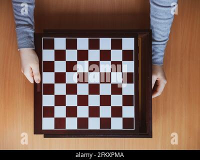les mains des enfants et le plateau d'échecs sur fond de bois vue de dessus Banque D'Images