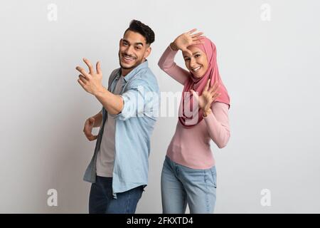 Joyeux couple musulman s'amuser ensemble sur fond gris, danser et rire Banque D'Images