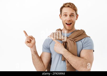 Image d'un ginger joyeux avec un corps en forme et sportif, dites wow, souriant excité et pointant vers le coin supérieur gauche, montrant l'annonce, recommandant Banque D'Images