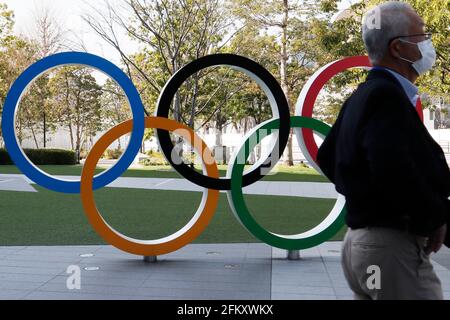 Tokyo, Japon. 04e mai 2021. Un homme portant un masque facial comme précaution contre la propagation du coronavirus, passe devant les anneaux olympiques près du stade national de Tokyo. Crédit : SOPA Images Limited/Alamy Live News Banque D'Images