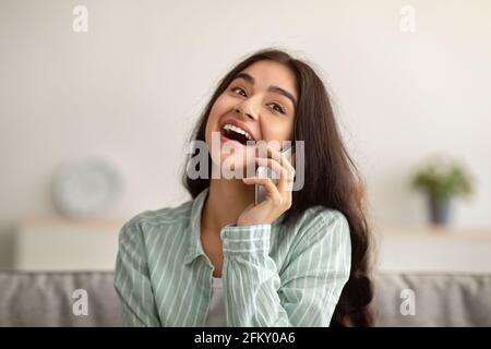 Portrait d'une femme indienne heureuse parlant sur un téléphone portable, ayant une conversation avec son ami à la maison Banque D'Images