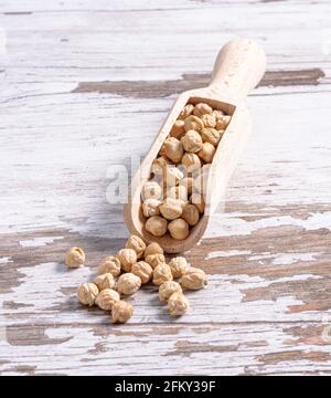 Gros plan de pois chiches dans une cuillère en bois rustique une planche en bois blanc Banque D'Images