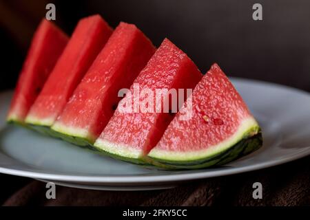 Un portrait en gros plan d'un quart coupé d'une pastèque. Le fruit est rouge au milieu avec des graines noires et a une peau verte rayée et est couché Banque D'Images