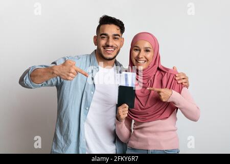 Tourisme halal. Portrait d'un couple musulman heureux avec passeports et billets Banque D'Images