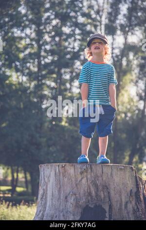 Jeune garçon se tenait sur un tronc d'arbre faisant différentes expressions Banque D'Images