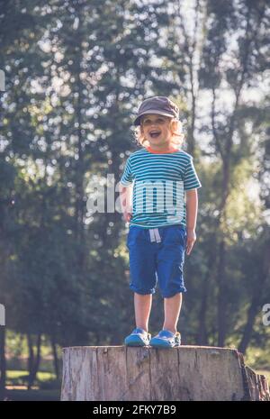 Jeune garçon se tenait sur un tronc d'arbre faisant différentes expressions Banque D'Images