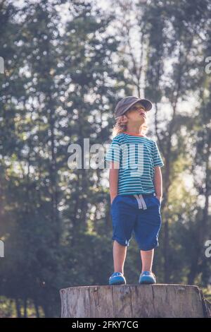 Jeune garçon se tenait sur un tronc d'arbre faisant différentes expressions Banque D'Images