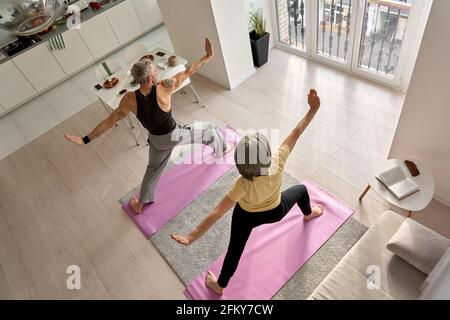 Faites de l'exercice de yoga guerrier à la maison en famille d'âge moyen. Banque D'Images