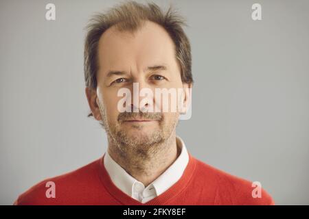 Portrait d'un homme de tête qui se contente de regarder l'appareil photo arrière-plan studio gris Banque D'Images