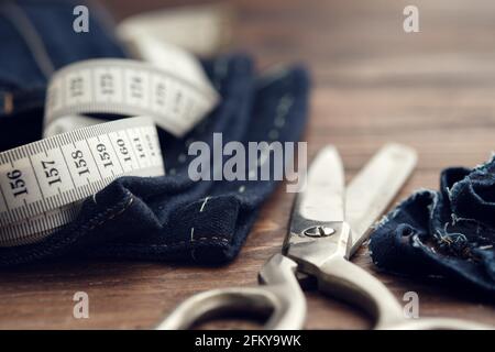 Shortening jeans. Ruban de mesure et ciseaux sur table. Coupe de jeans. Banque D'Images